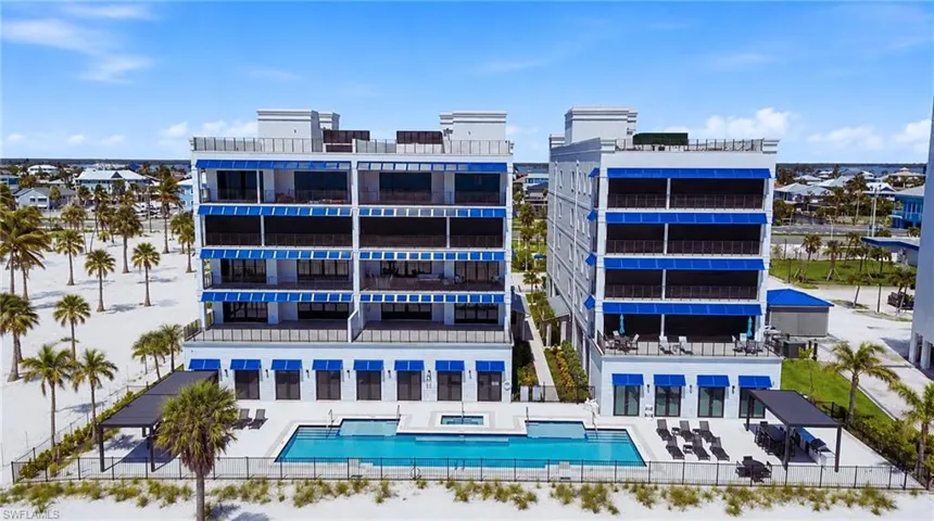 Modern oceanfront residential complex featuring contemporary architectural design with multi-story glass and metal facade, expansive resort-style saltwater swimming pool, direct beach access, and integrated ground-level retail or amenity spaces - Virtually Edited Image
