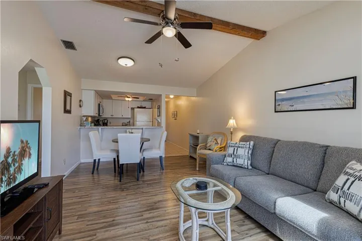 Living room featuring dark wood-style flooring, a ceiling fan, and a textured ceiling