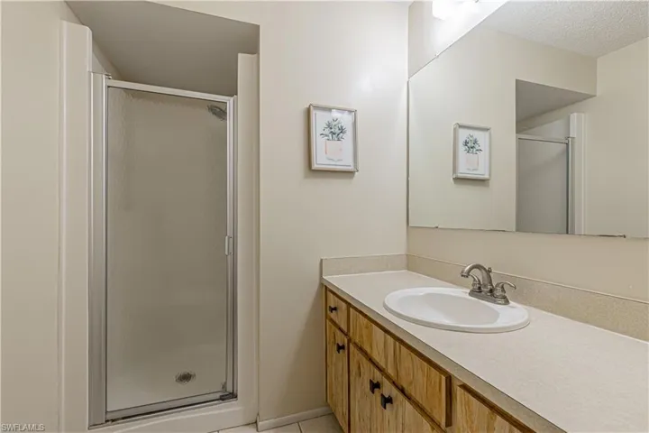 Bathroom featuring a shower stall, vanity, light tile patterned floors, and a textured ceiling
