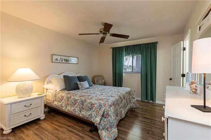 Bedroom with a textured ceiling, dark wood-style floors, and ceiling fan
