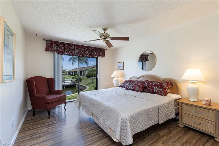 Bedroom with access to outside, a textured ceiling, dark wood finished floors, and ceiling fan