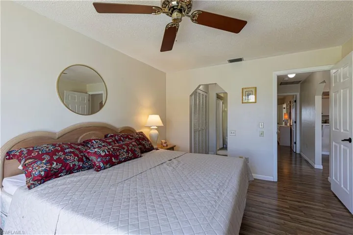 Bedroom with a textured ceiling, dark wood-style flooring, a ceiling fan, and a closet