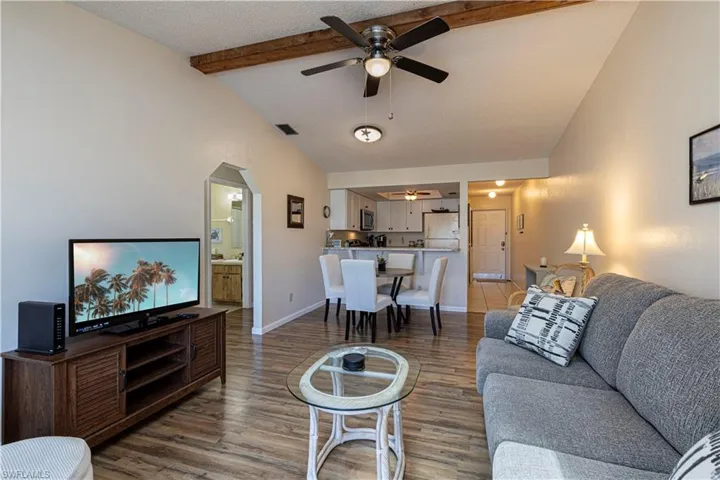 Living room with a textured ceiling, wood finished floors, a ceiling fan, and arched walkways