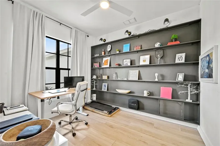Office featuring wood finished floors, ceiling fan, built in shelves, and baseboards