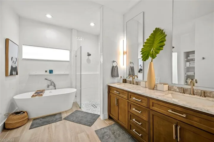 Full bath featuring double vanity, a soaking tub, tiled shower, and recessed lighting