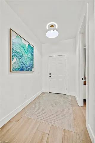 Foyer with light wood finished floors and baseboards