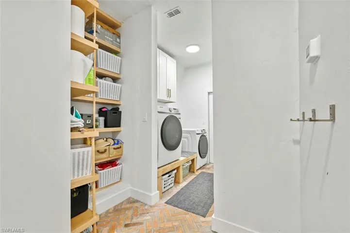 Corridor featuring brick floors and baseboards