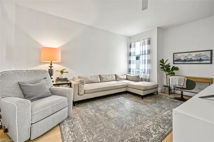 Living area with light wood-style floors and a ceiling fan