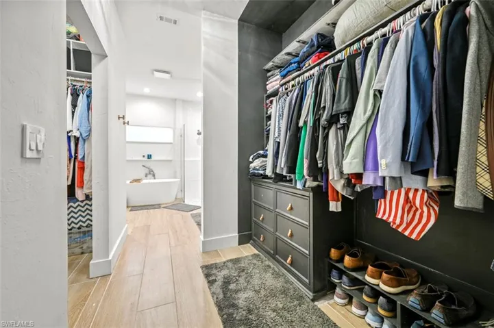 Walk in closet with light wood finished floors