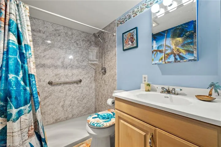 Bathroom featuring vanity, toilet, and curtained shower