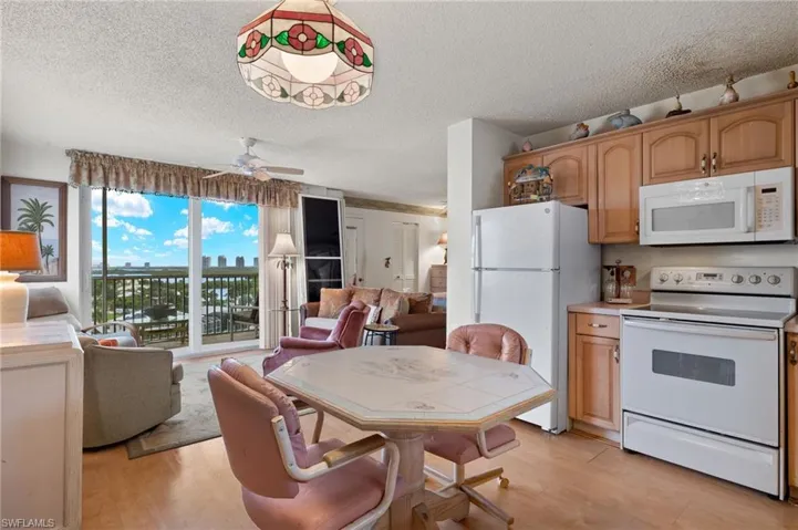 Kitchen with a textured ceiling, ceiling fan, light wood-type flooring, white appliances, and tile countertops
