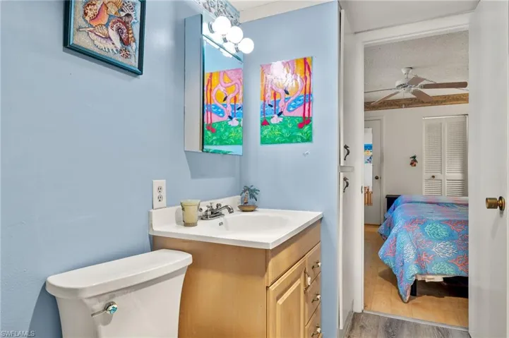 Bathroom featuring a textured ceiling, toilet, vanity, hardwood / wood-style flooring, and ceiling fan