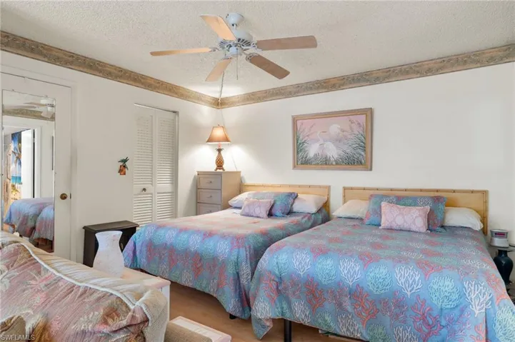 Bedroom with ceiling fan, wood-type flooring, a textured ceiling, and a closet