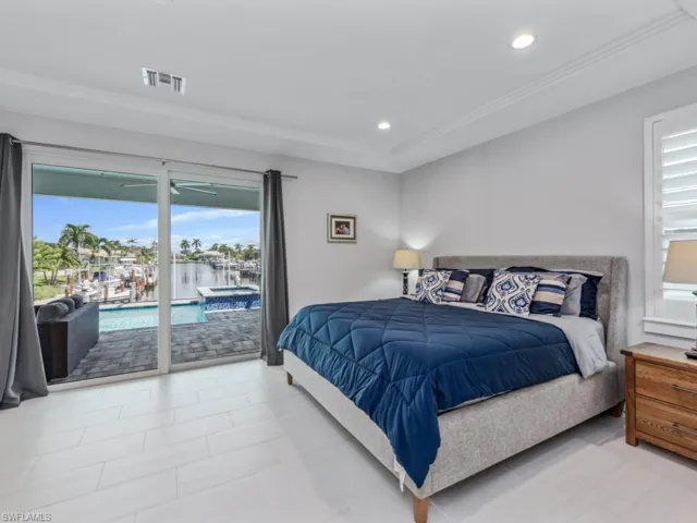 Tiled bedroom with a water view, access to exterior, and recessed lighting