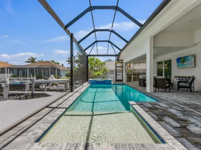 View of swimming pool featuring a sunroom, a patio area, glass enclosure, and a pool with connected hot tub