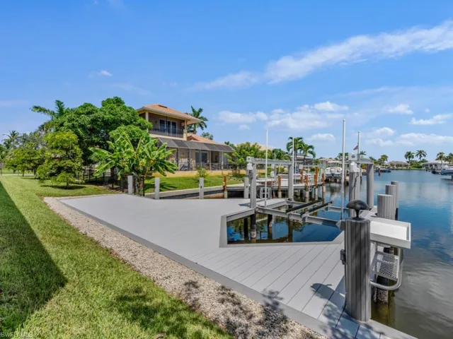 Dock featuring boat lift, a water view, and a yard