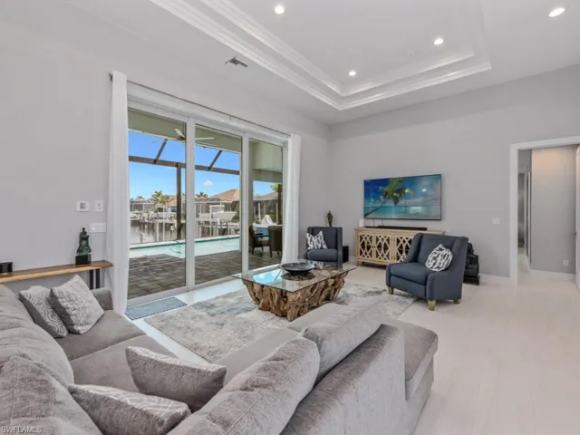 Living room with recessed lighting, a raised ceiling, a sunroom, and ornamental molding