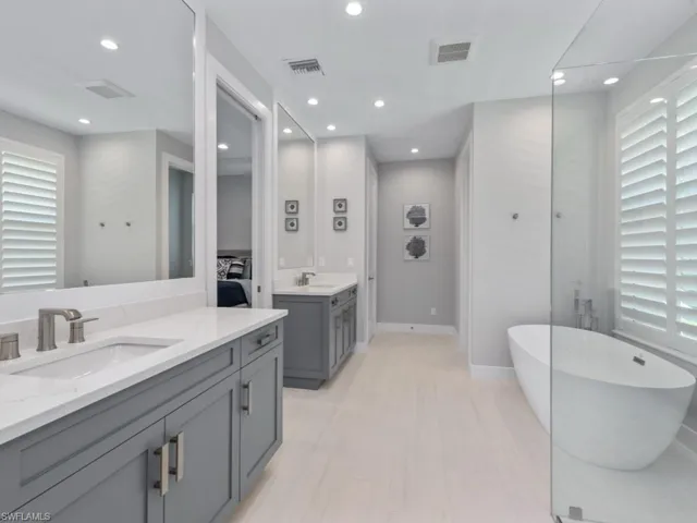 Bathroom with a freestanding tub, two vanities, and recessed lighting