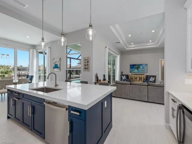 Kitchen featuring open floor plan, blue cabinetry, decorative light fixtures, wine cooler, and dishwasher