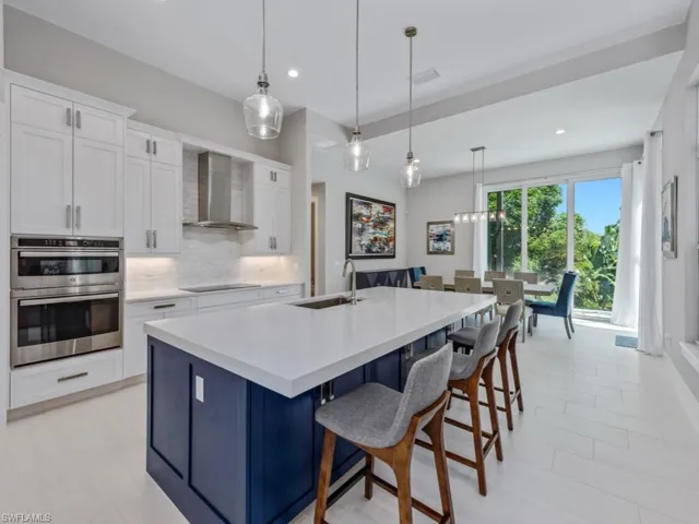 Kitchen with blue cabinetry, white cabinets, pendant lighting, backsplash, and a breakfast bar