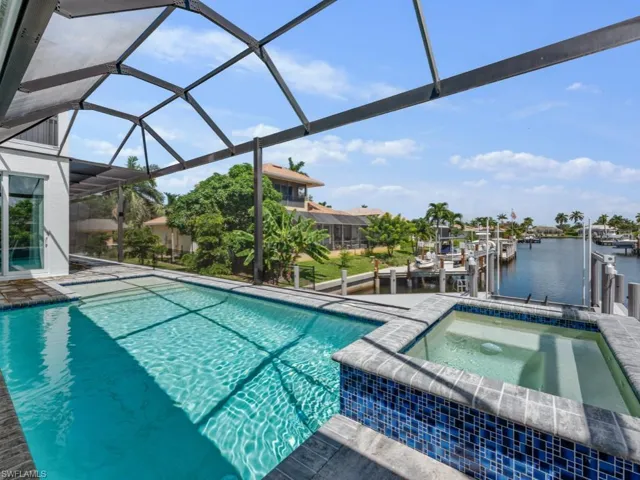View of swimming pool with a water view, a patio area, a sunroom, glass enclosure, and a pool with connected hot tub