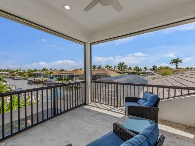 Balcony featuring a water view, ceiling fan, and a residential view