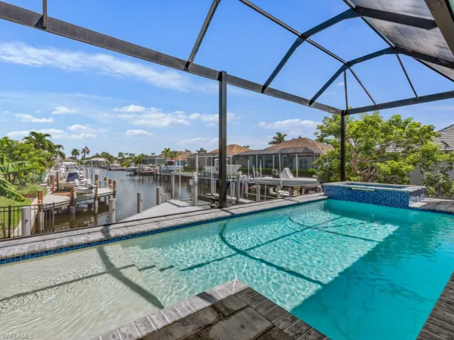 View of pool featuring a water view, boat lift, a boat dock, a sunroom, and a pool with connected hot tub