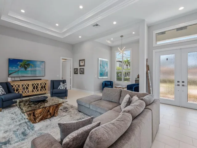 Living area with a tray ceiling, french doors, recessed lighting, ornamental molding, and a high ceiling