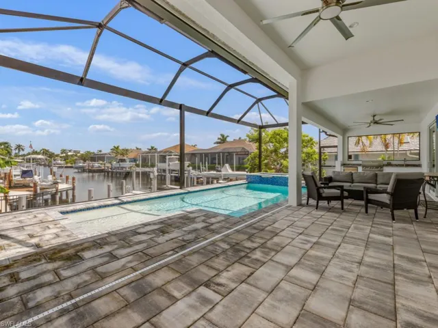 View of pool with a sunroom, a water view, a patio area, a ceiling fan, and a boat dock