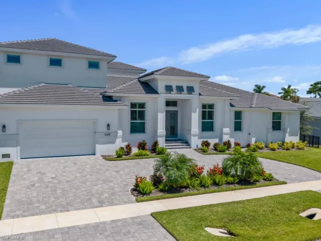 View of front of home with decorative driveway, a tiled roof, stucco siding, and a front lawn