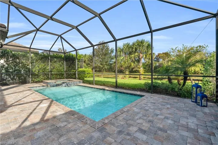 View of swimming pool with an in ground hot tub, a patio, and a lanai