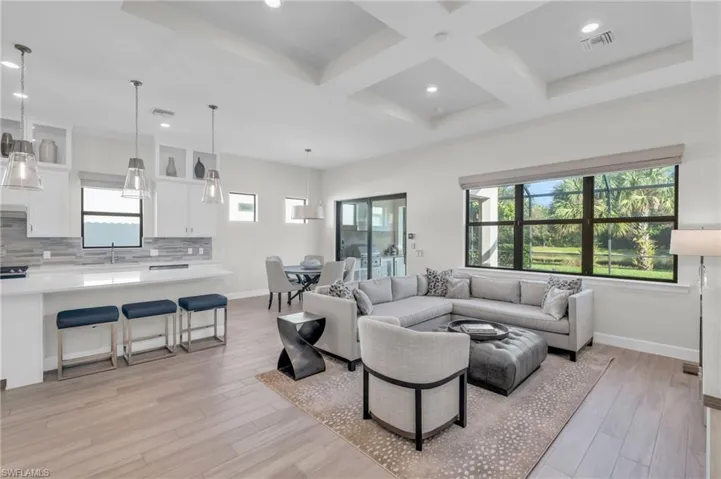 Living room with light hardwood / wood-style floors, coffered ceiling, beamed ceiling, and sink