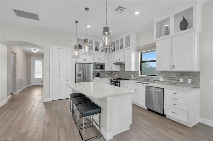 Kitchen with stainless steel appliances, light hardwood / wood-style flooring, a kitchen island, and white cabinets