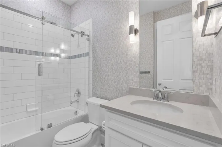 Full bathroom featuring vanity, toilet, and enclosed tub / shower combo