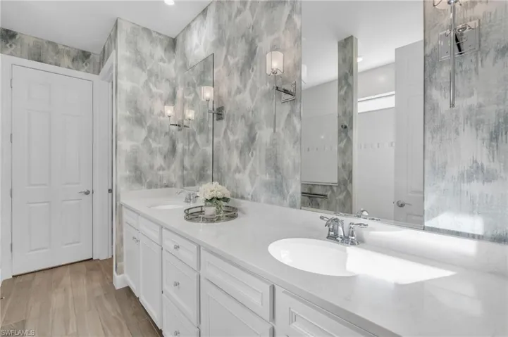 Bathroom with vanity, a tile shower, and wood-type flooring