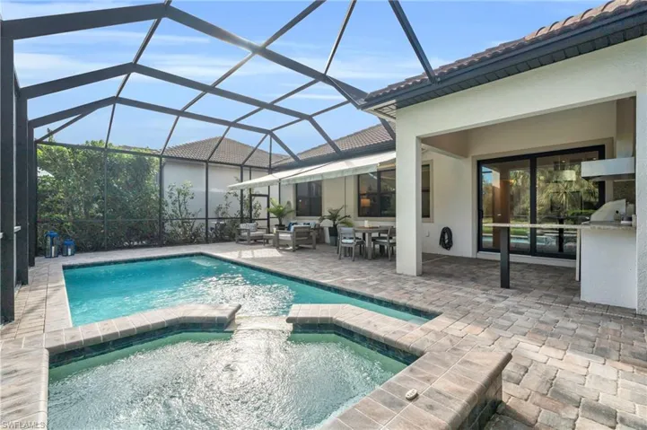 View of pool with an in ground hot tub, a patio area, and glass enclosure