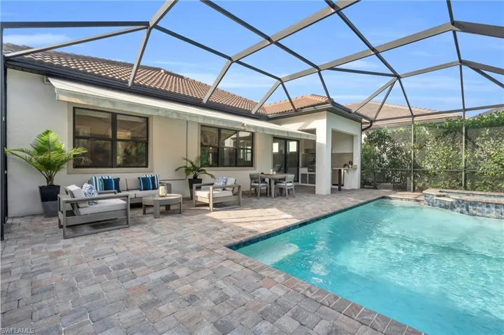 View of swimming pool with an in ground hot tub, an outdoor living space, a patio, and a lanai