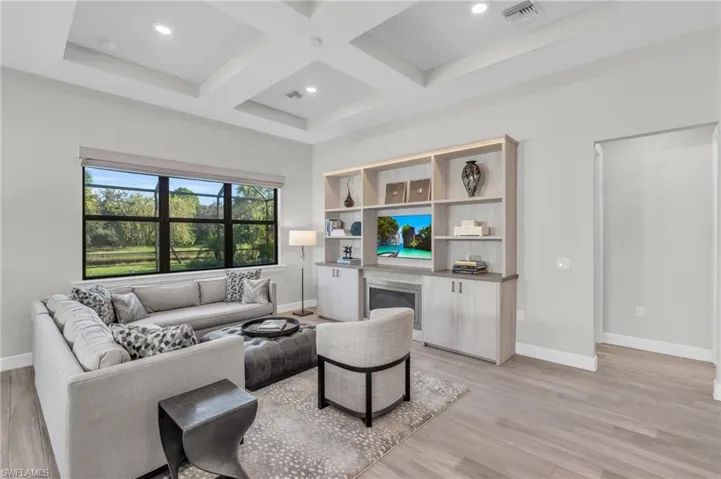 Living room with beam ceiling, coffered ceiling, and light wood-type flooring