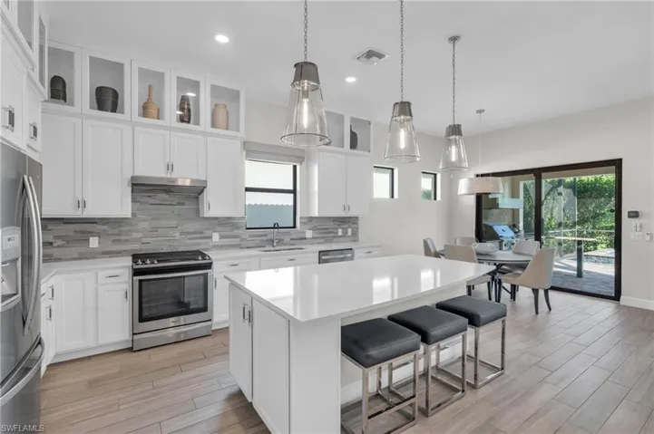 Kitchen featuring a kitchen island, stainless steel appliances, sink, plenty of natural light, and white cabinetry