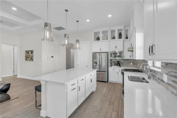 Kitchen with a kitchen island, white cabinets, stainless steel appliances, and light hardwood / wood-style floors