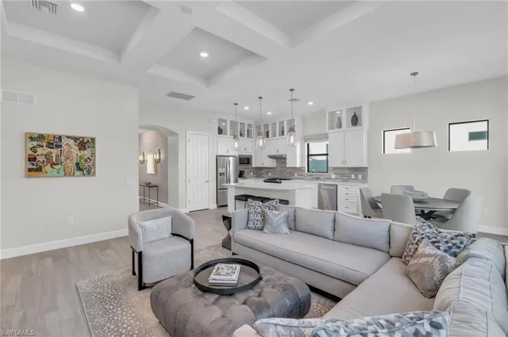Living room with beamed ceiling, coffered ceiling, and light wood-type flooring