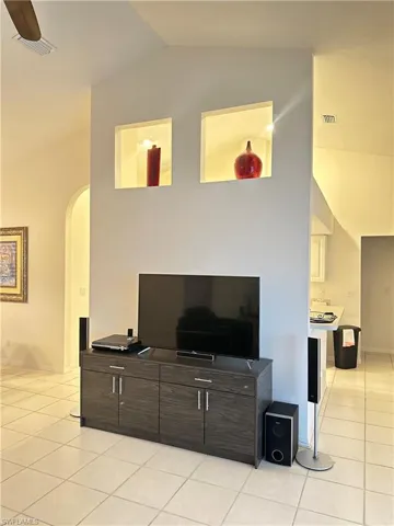 Living room with arched walkways, lofted ceiling, and light tile patterned floors