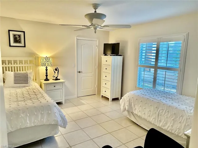 Bedroom featuring light tile patterned floors, baseboards, and ceiling fan