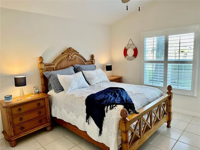 Bedroom featuring multiple windows, light tile patterned flooring, baseboards, and vaulted ceiling