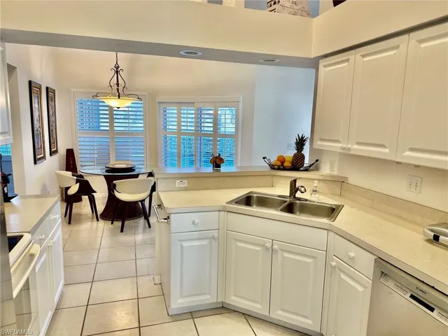 Kitchen with dishwashing machine, a sink, stove, light countertops, and a peninsula