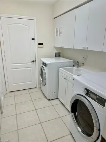 Washroom featuring cabinet space, washer and dryer, and light tile patterned floors