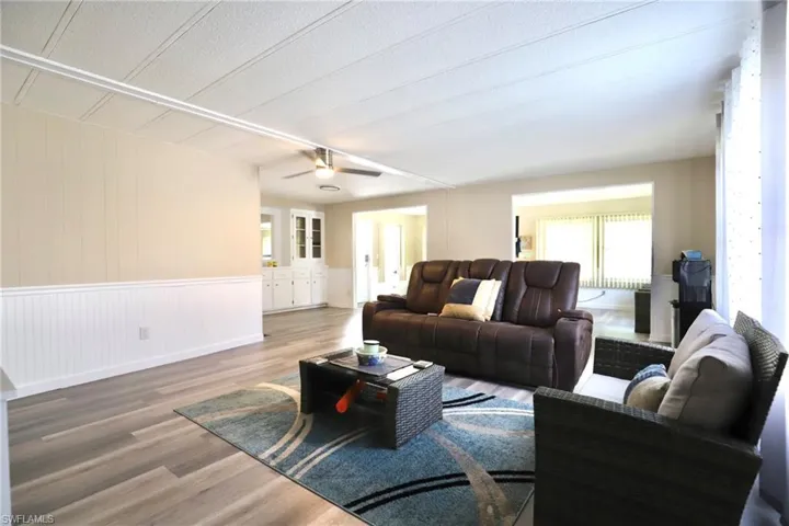 Living room with a textured ceiling, wood-type flooring, wooden walls, and ceiling fan