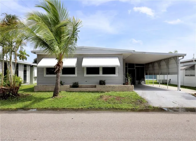 View of front facade with a carport and a front lawn
