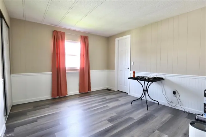 Spare room with a textured ceiling, wooden walls, and hardwood / wood-style floors