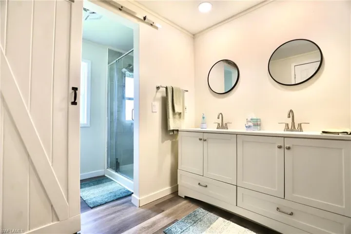Bathroom with vanity, hardwood / wood-style flooring, crown molding, and a shower with door